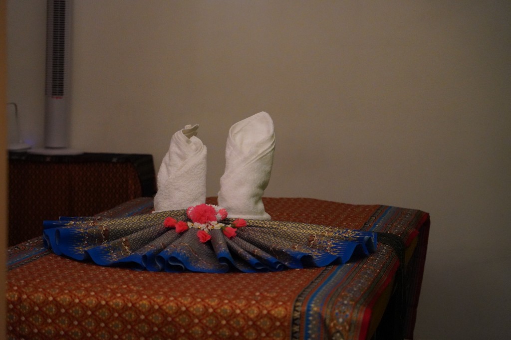 Gefaltete Handtücher und Blumen auf der Massage-Liege